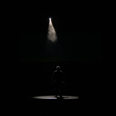 Zanger met microfoon op een groot concertpodium in felle spotlights