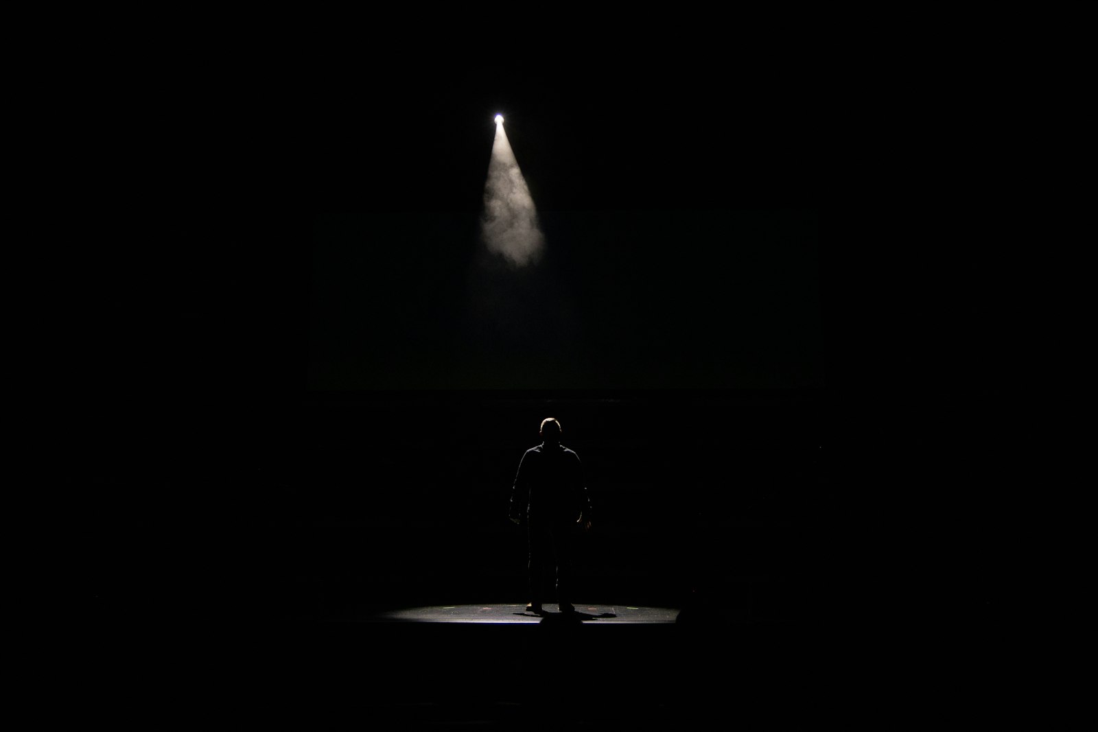 Zanger met microfoon op een groot concertpodium in felle spotlights