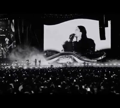 Dua Lipa zingt op het grote scherm boven een vol stadion tijdens haar Radical Optimism Tour