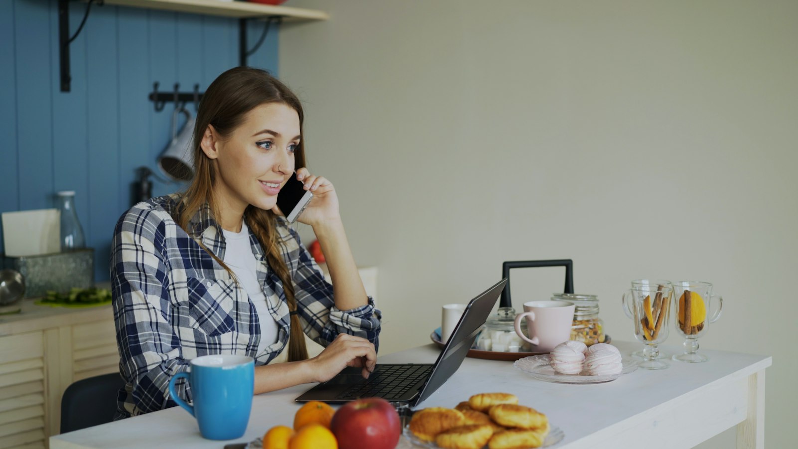 Vrouw werkt op een laptop aan de keukentafel thuis met een kop koffie